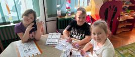Dzieci pozują do zdjęcia w trakcie malowania kolorowanek przedstawiających skarpety