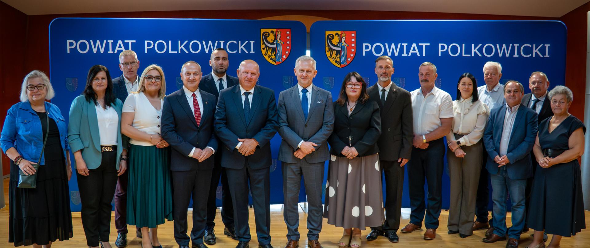 Osoby uśmiechają się, stoją na sali. 
