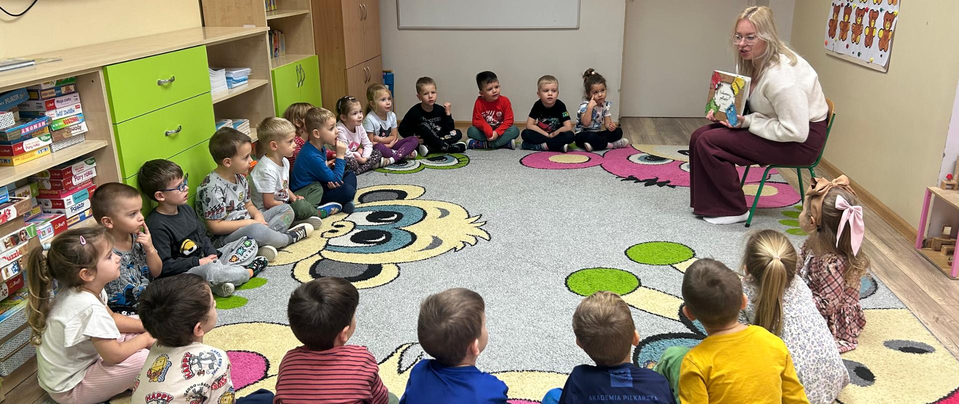 Grupa dzieci słucha bajki czytanek przez rodzica w ramach akcji "Cała Polska Czyta Dzieciom"