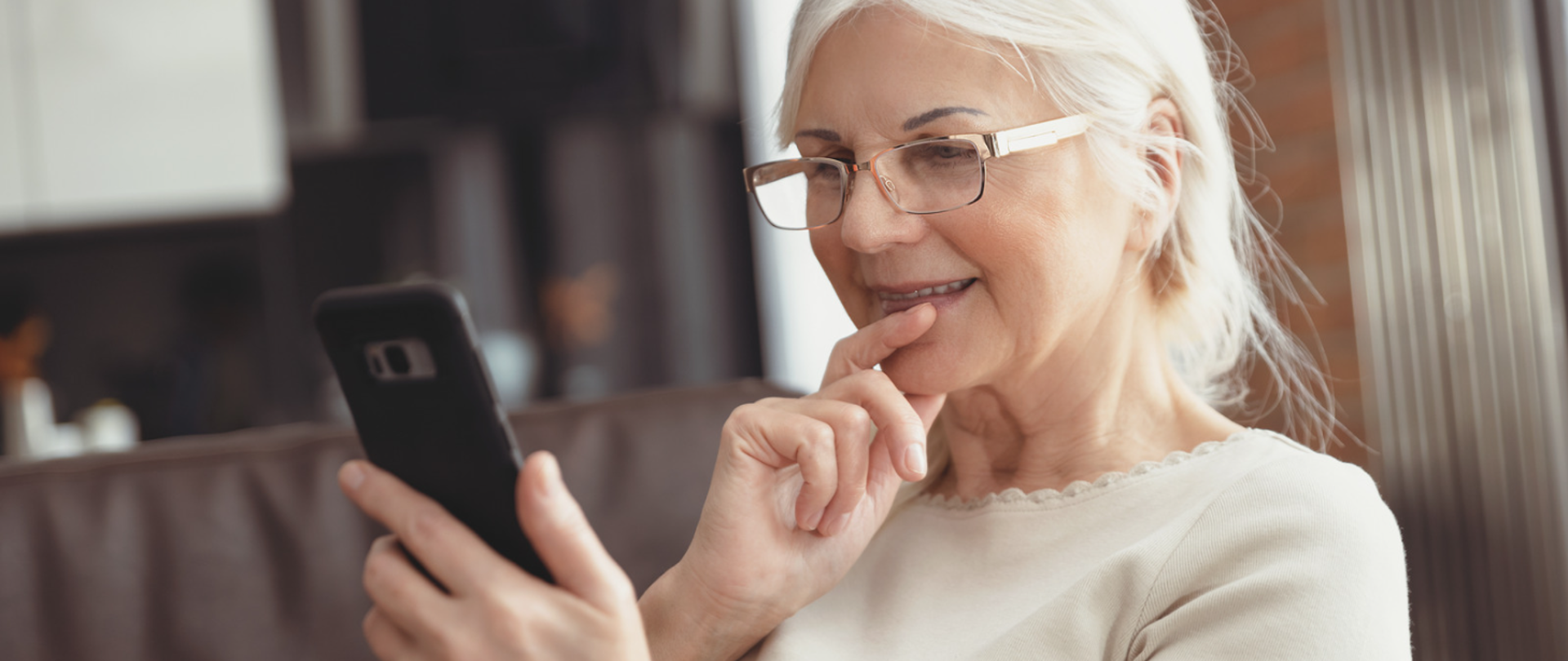 Kobieta w wielu emerytalnym w dłoni trzyma telefon typu smartfon