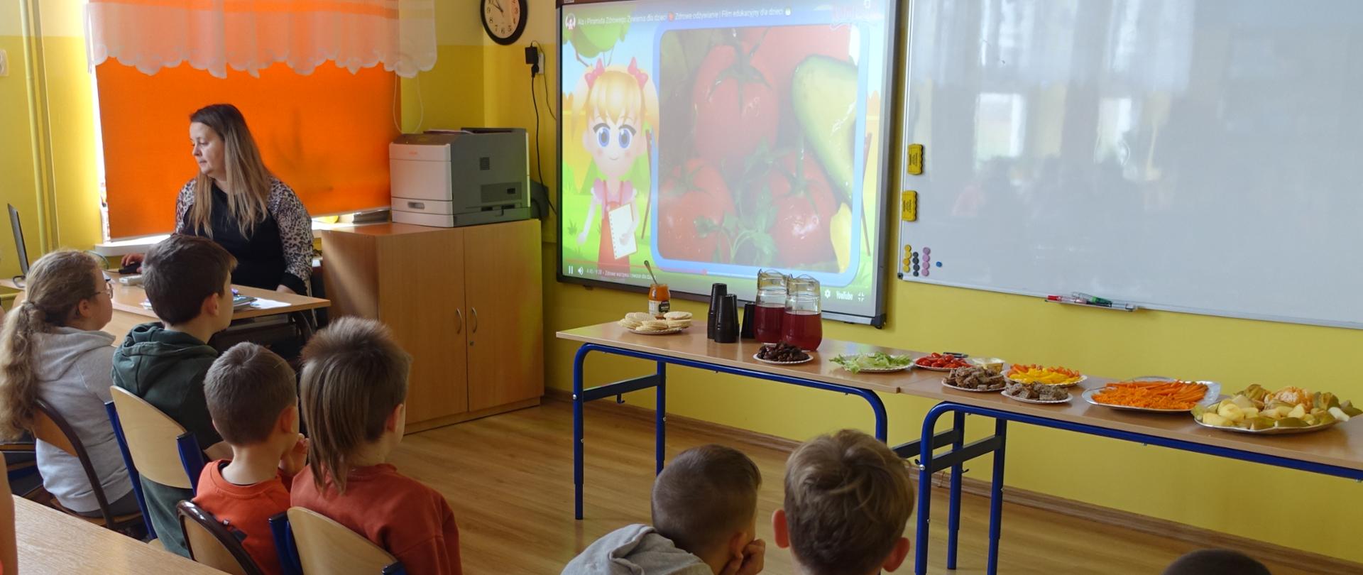 Uczniowie w sali lekcyjnej słuchają prelekcji pedagoga szkolnego