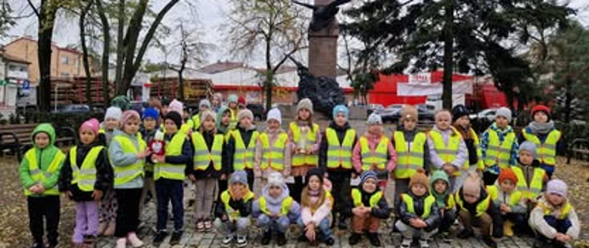 Dzieci w odblaskowych koszulkach przy pomniku