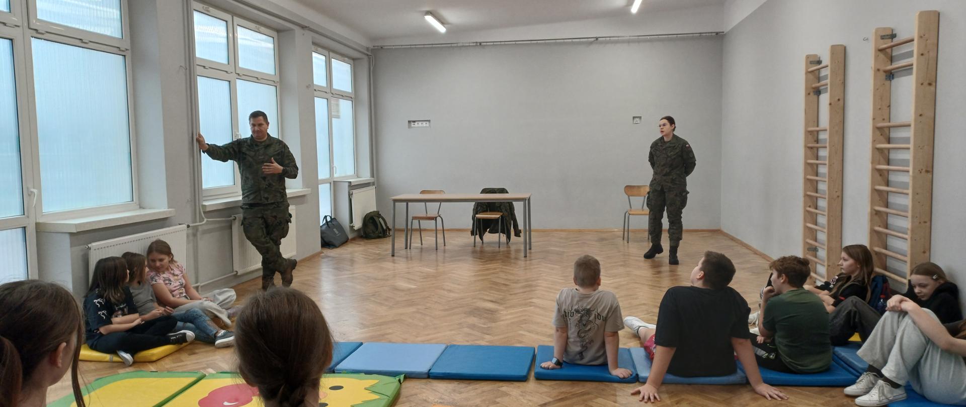 Zdjęcie przedstawia żołnierzy i uczniów podczas prelekcji "Edukacja z Wojskiem".