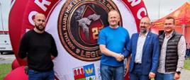 Starosta Przasnyski Krzysztof Bieńkowski wsparł zbiórkę krwi dla Szymonka z Krasnego. Zdjęcie wykonano podczas akcji krwiodawstwa przeprowadzonej pod hasłem "Siła w jedności", która odbyła się w Ostrołęce. Zdjęcie przedstawia od lewej: Adama Krawczyka, Pawła Stawickiego i Krzysztofa Bieńkowskiego ściskających dłonie, Daniela Grędzińskiego. W tle dmuchana kropla krwi z napisem: Zdrowi Dawcy oraz logo Legionu Honorowych Dawców Krwi przy 2. Ośrodku Radioelektronicznym w Przasnyszu i herb Powiatu Przasnyskiego.