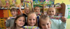 Chłopcy stoją w klasie szkolnej, pokazują otrzymane lody