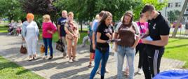 Festyn Profilaktyczno Zdrowotny w ogrodach przasnyskiego szpitala. Zdjęcie przedstawia trenerów personalnych "Rzeźbiarnia Gym&Med" omawiających wyniki pomiarów uczestniczki Festynu.