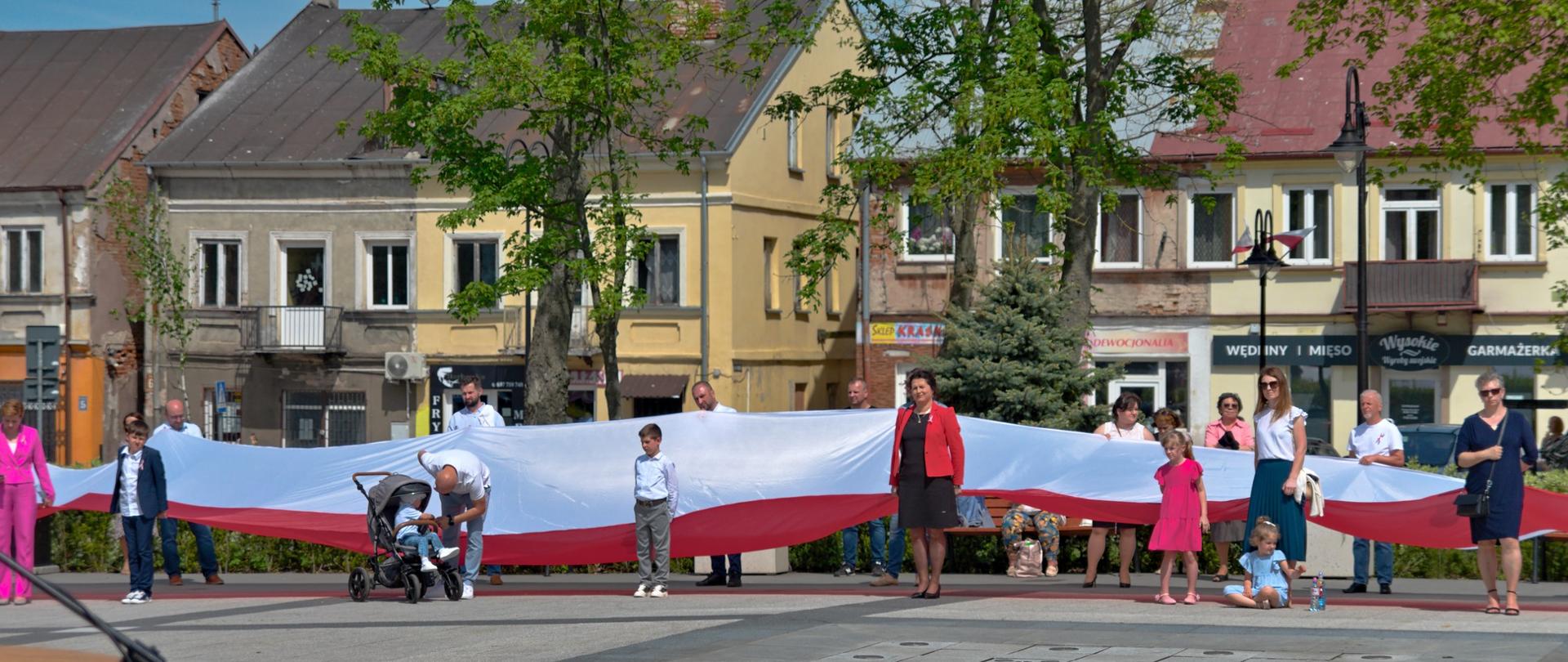 Uczestnicy obchodów trzymają ogromną flagę Polski