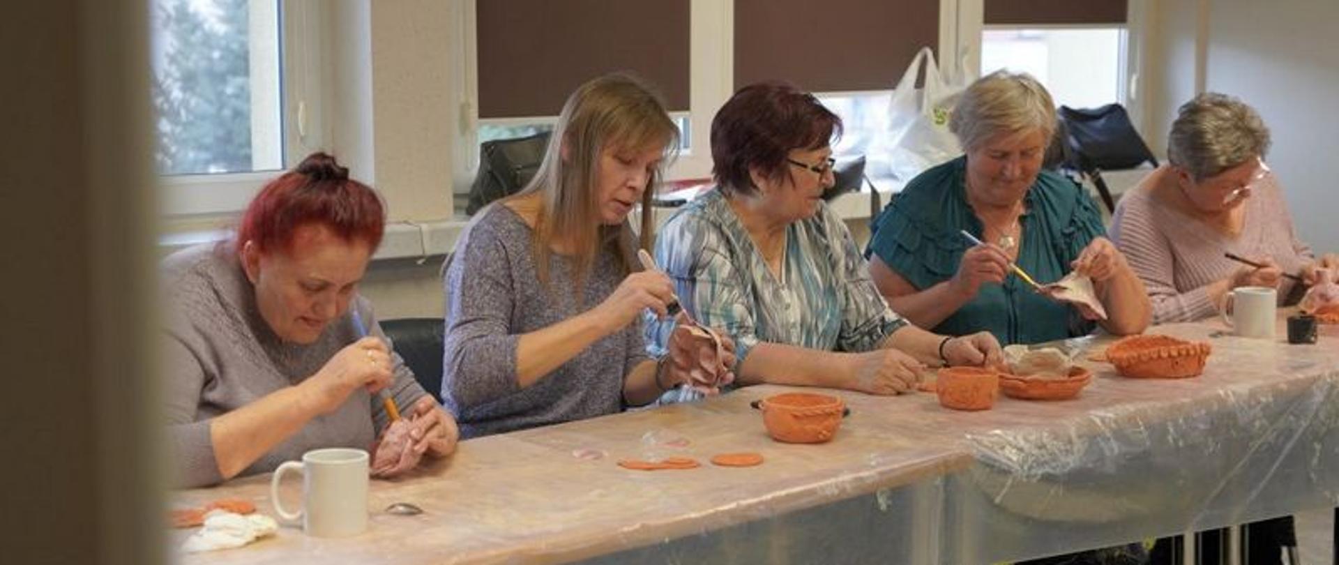 Seniorzy biorą udział w warsztatach ceramicznych „Ogień i glina”, podczas których własnoręcznie wykonują ozdoby i naczynia z gliny
