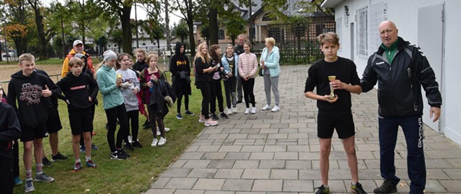 Starsi sportowcy odbierają puchary od organizatora