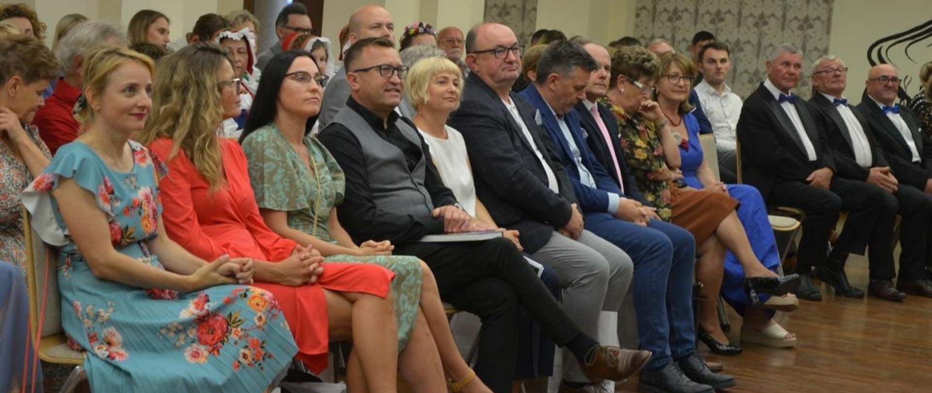 Zebrani na promocji książki w bibliotece słuchają wystąpień zaproszonych gości