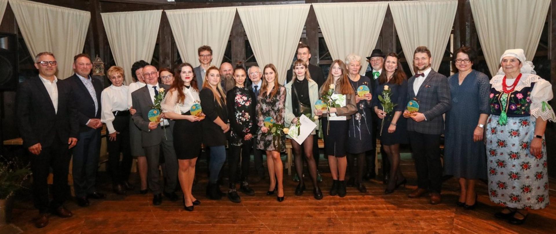 Grupa laureatów nagród starosty, wnioskodawcy oraz włodarze powiatu w altanie w skansenie