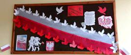 Gazetka ścienna przedstawiająca symbole świąteczne: godło, flagę, gołąbki, kontury mapy Polski z narysowanym w środku orłem, wycięte z papieru postacie chłopca i dziewczynki trzymające flagę oraz napis KONSTYTUCJA 3 MAJA