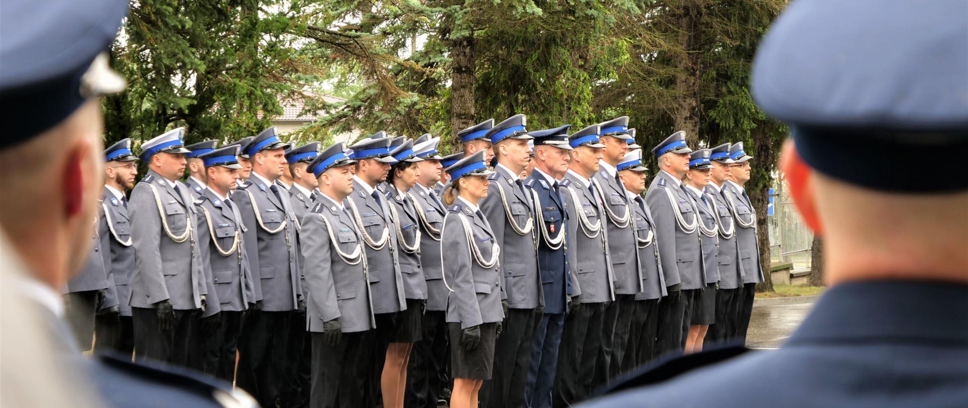 Zdjęcie przedstawia kilkadziesiąt osób stojących w rzędzie w mundurach.