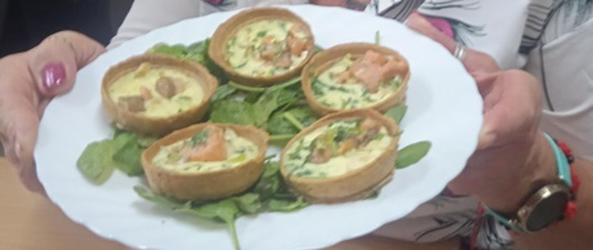 kobieta siedzi za stołem, w rękach trzyma talerz z tortellini 