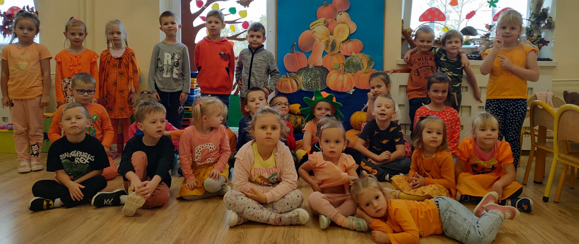 Wspólne zdjęcie wszystkich przedszkolaków na tle dekoracji z okazji Dnia Dyni.