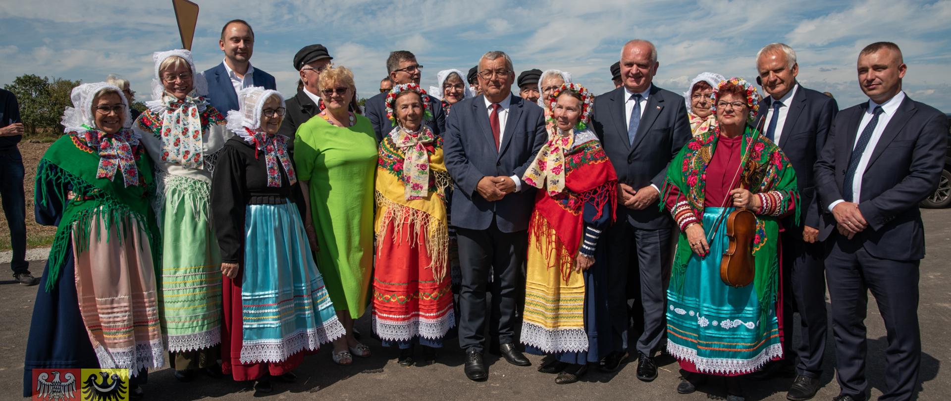 mężczyzni w garniturze i ludzie w strojach ludowych na drodze
