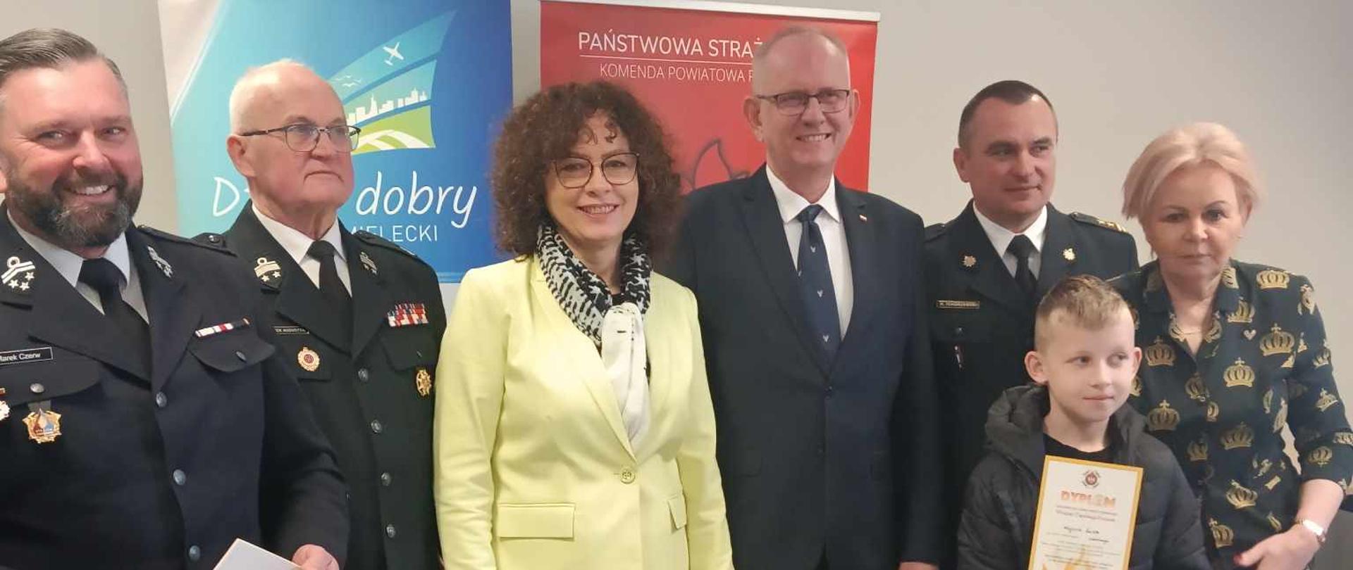 Zdjęcie przedstawia ucznia wraz z przedstawicielami Straży Pożarnej, Panie Posłanki - Krystynę Skowrońską i Elżbietę Burkiewicz, oraz Pana Posła Fryderyka Kapinosa