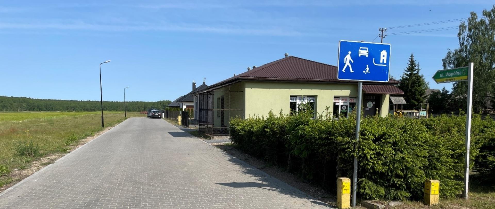 Ulica wykonana z kostki brukowej, po prawej stronie 4 budynki.