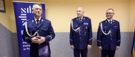 Trzech policjantów stoi przy żółtej ścianie