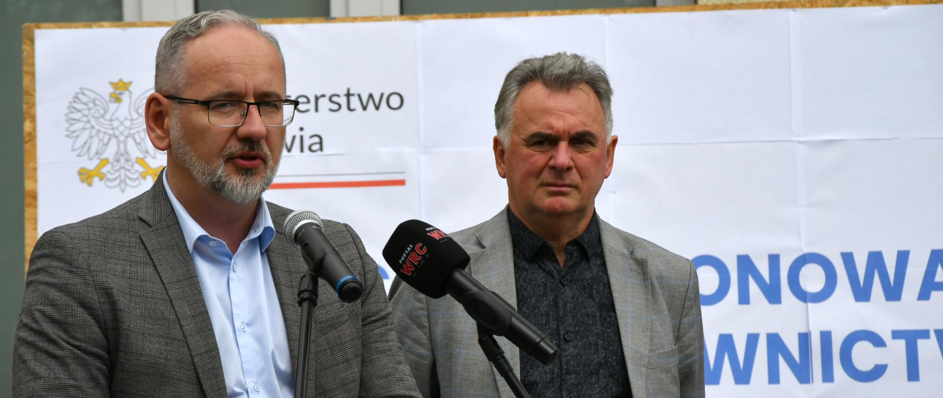 Minister Zdrowia Adam Niedzielski z Burmistrzem Miasta i Gminy Margonin Januszem Piechockim stoją przed mównicą i szyldem mówiącym o stacjonującej karetce w Margoninie.