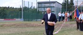 Ks. Piotr Chodźko niąsący chleb