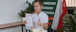 Uczeń pozuje z dyplomem i nagrodą