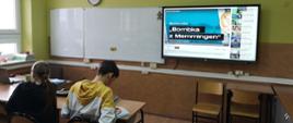 Uczniowie od tyłu, na ekranie multimedialnym napis Bombka z Memmingen