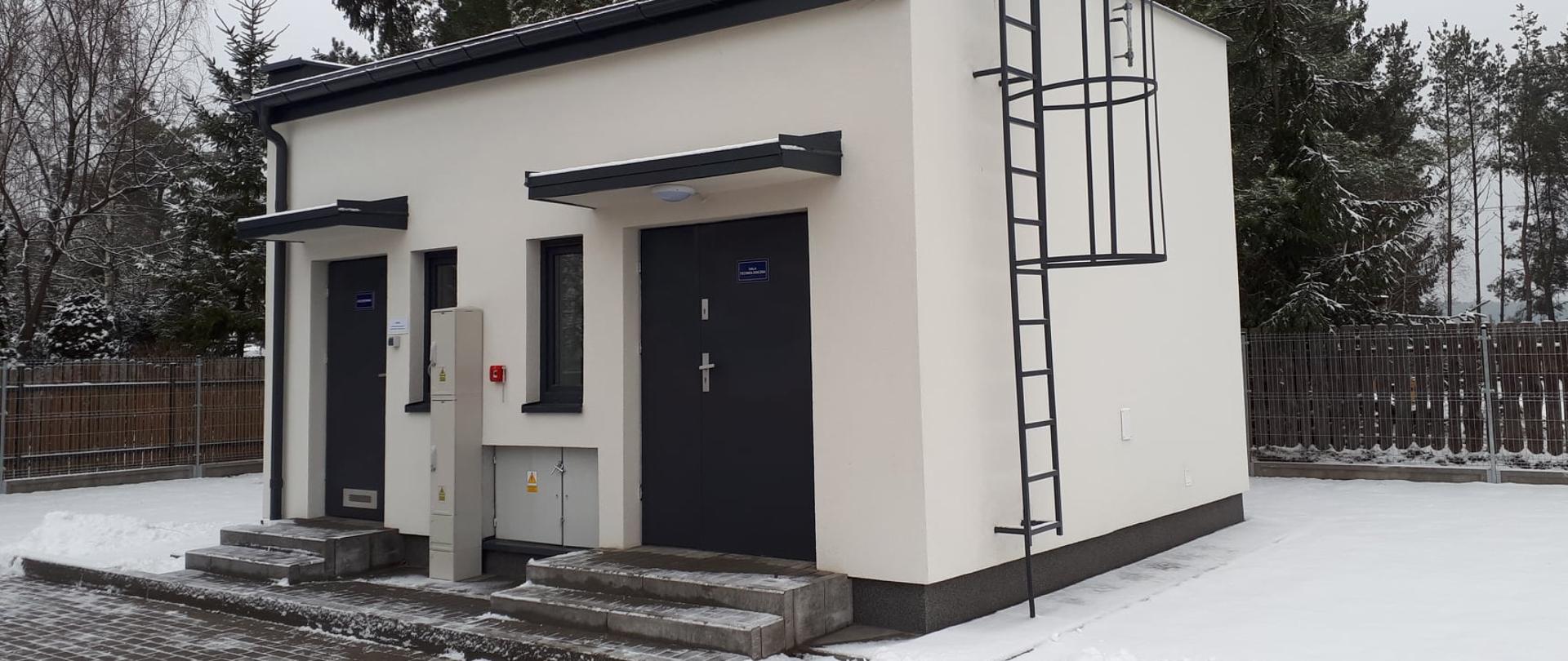 Odremontowany budynek stacji wodociągowej w Udrzynie. Dwa wejścia, dwa okienka. Po prawej stronie znajduje się drabinka na dach.