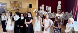 Uczniowie ubrani w stroje zakonnic, aniołów odgrywają swoje role na przedstawieniu