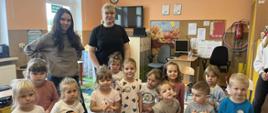 Dwie uczennice klasy ósmej pozują z grupą przedszkolaków do wspólnego zdjęcia.