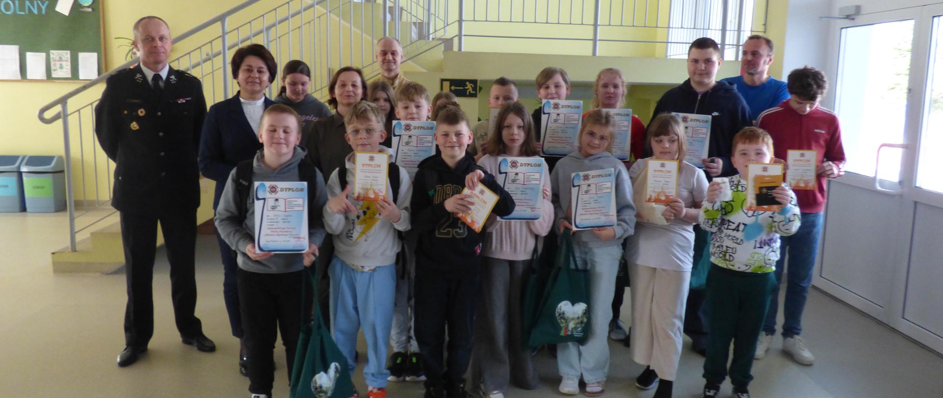 Zdj. 8 – przedstawia zdjęcie grupowe wszystkich uczestników biorących udział w Gminnym etapie Ogólnopolskiego Turnieju Wiedzy Pożarniczej wraz z przedstawicielami komisji jury
i organizatorami. Uczniowie radośnie eksponują otrzymane dyplomy i upominki.
