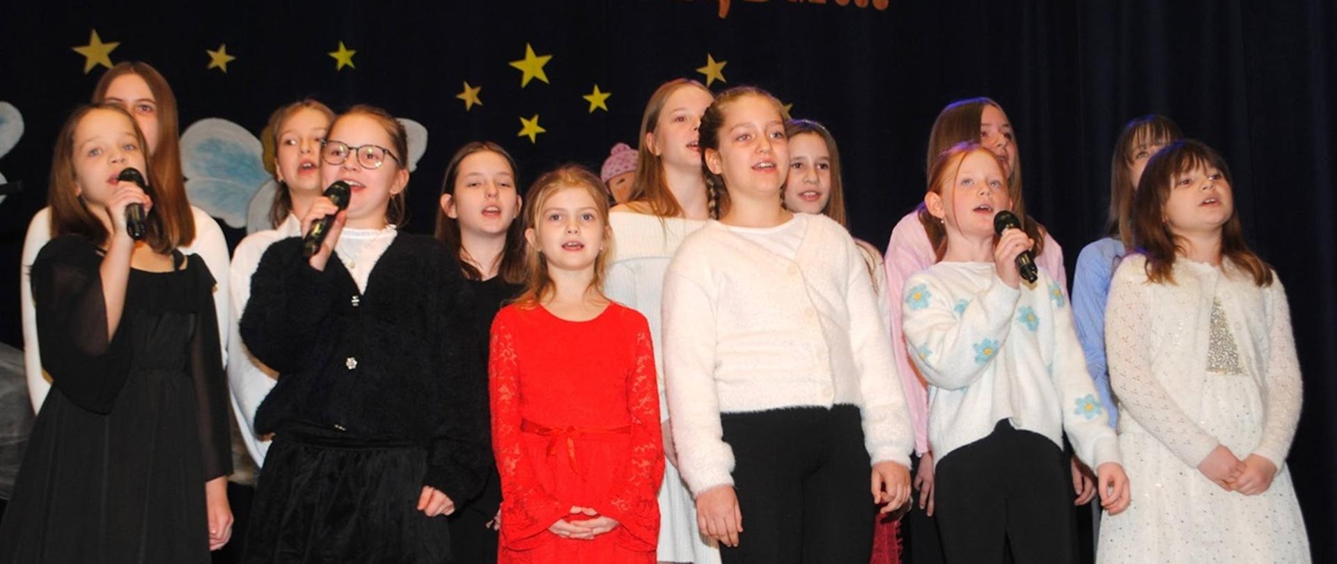 kilkanaście dziewczynek stoi na scenie i śpiewa