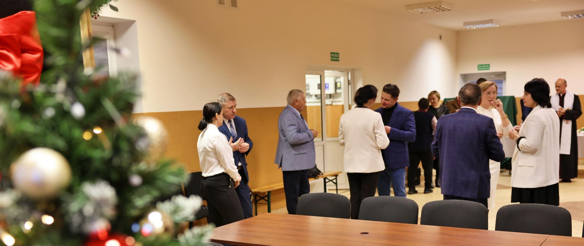 ludzie podczas spotkania wigilijnego, składają sobie zyczenia i łamią się opłatkiem