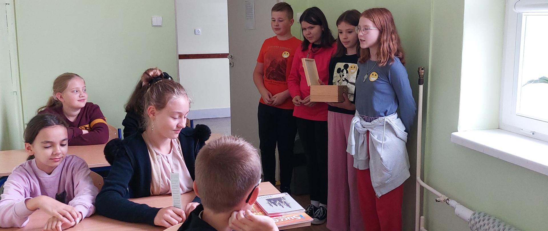 Uczniowie klasy VI wręczają uśmiechnięte buźki klasie IV.