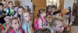 Dzieci zwiedzają zabytkową izbę z 19. wieku, w której znajdują się rzeźby religijne