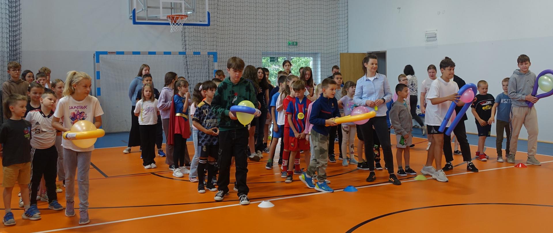 Uczniowie biorą udział w konkurencji sportowej z wykorzystaniem makaronów i balonów
