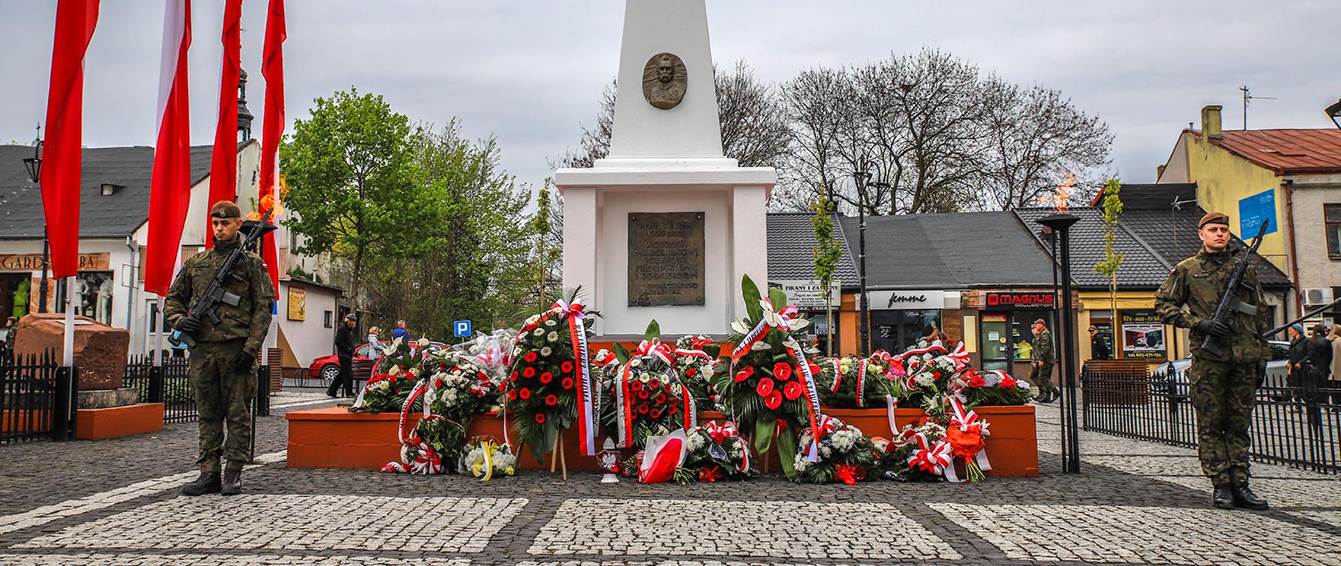 Zdjęcie przedstawia wartę żołnierzy przy pomniku Józefa Piłsudskiego w Kraśniku. Przy pomniku zostały złożone kwiaty, znicze i wiązanki. Na lewo od pomnika powiewają biało czerwone flagi.