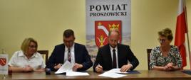Przy biurku przedstawiciele Zarządu Powiatu Proszowickiego oraz Gminy Pałecznica podpisują umowę na "Wyrównywanie różnic między regionami III”