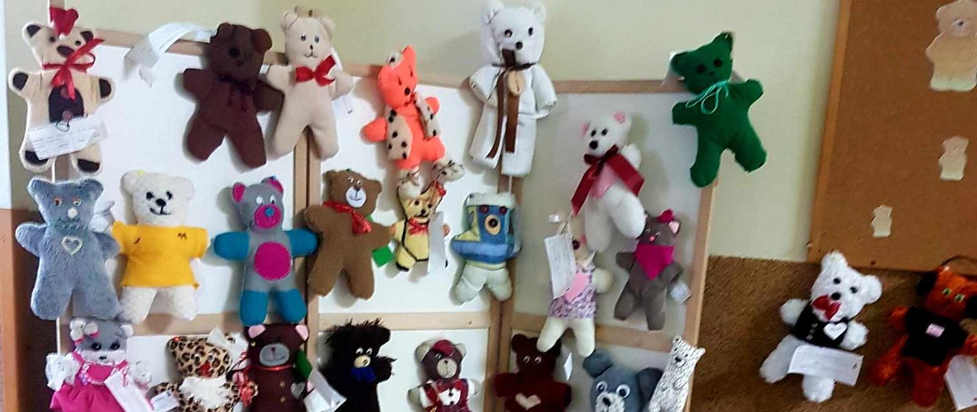 Ścianka z zawieszonymi różnobarwnymi misiami, uszytymi przez uczniów w ramach szkolnego konkursu "Uszyj pluszowego misia"