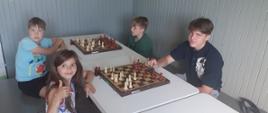 Uczestnicy siedzą przy szachach, rozgrywają potyczki