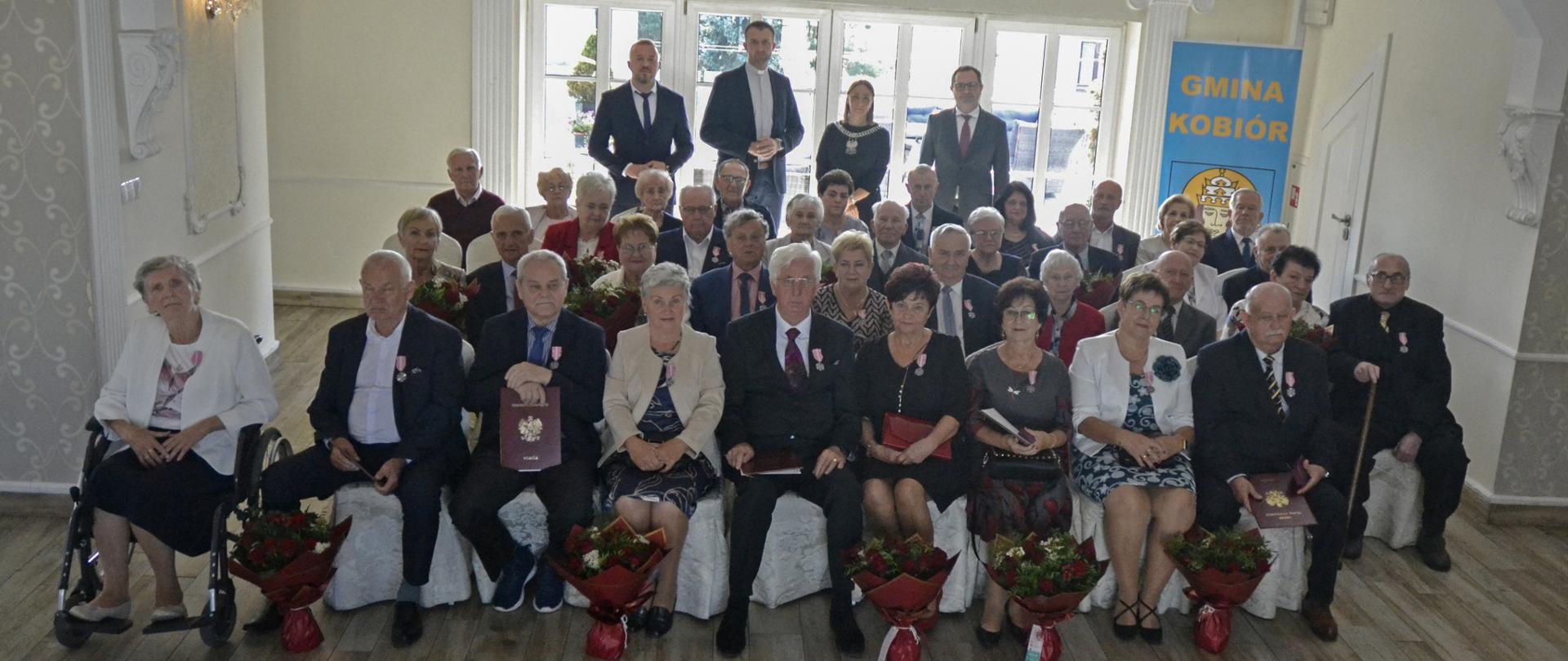 Grupa osób pozuje do zdjęcia w jasnej sali