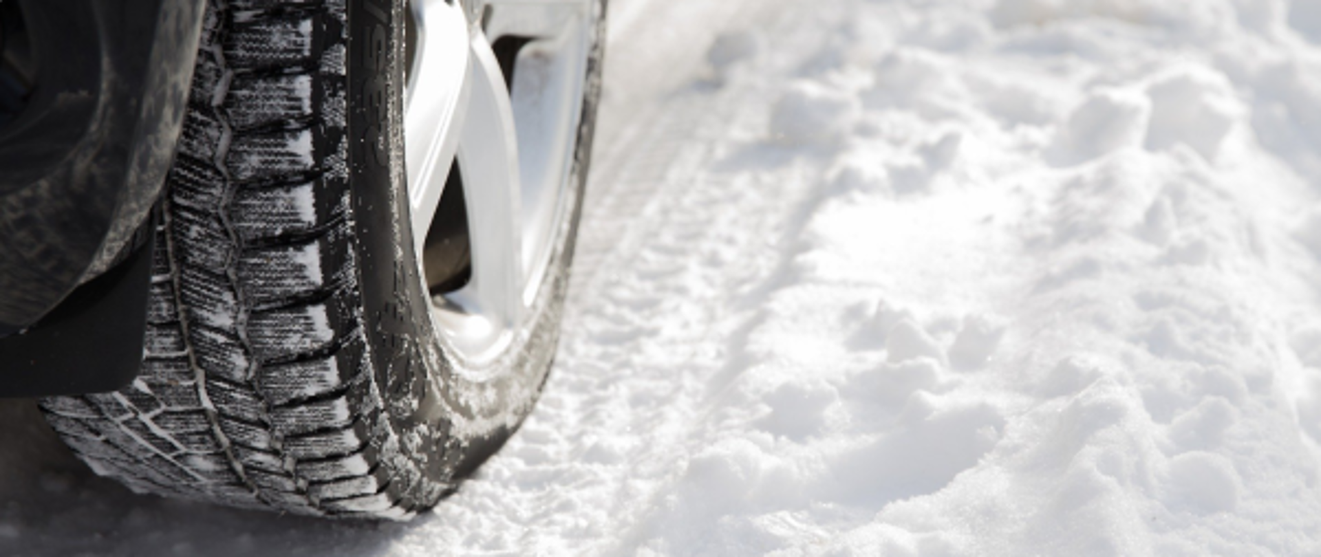 Zbliżenie na koło samochodu na pokrytej śniegiem drodze
