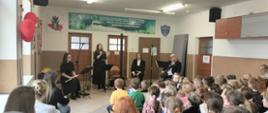 Na scenie znajduje się czworo muzyków - dwie kobiety i dwóch mężczyzn. Wszyscy ubrani są na czarno. Jedna z Pań śpiewa przez mikrofon. 