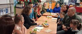 Rodzice z dziećmi siedzą przy stole, przygotowują gwiazdy z papieru