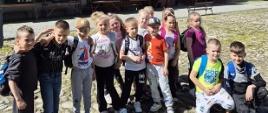 Dzieci przedszkolne stoją na placu Miasteczka Galicyjskiego, na kamiennym podłożu, za nimi budynki z 19. wieku