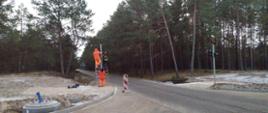 Zdjęcie przedstawia robotników instalujących sygnalizację świetlną .