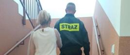 Instruktaż pomocy osoby niewidomej - strażak pomaga osobie niewidomej wejść po schodach