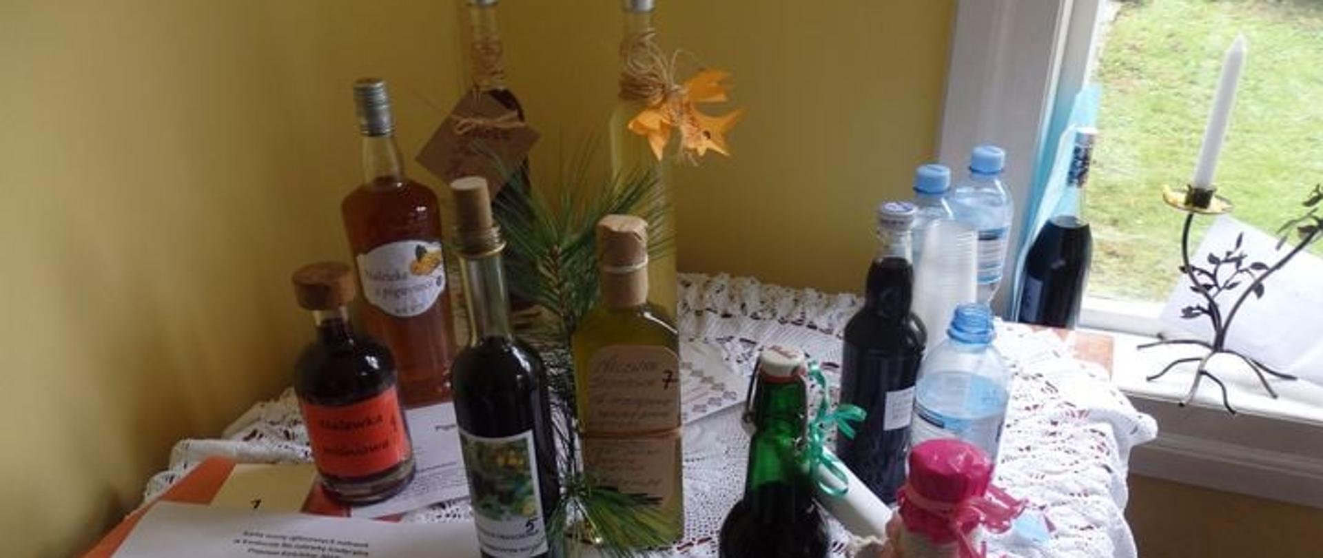 butelki z nalewkami stojącymi na stole przykrytym koronkowym obrusem