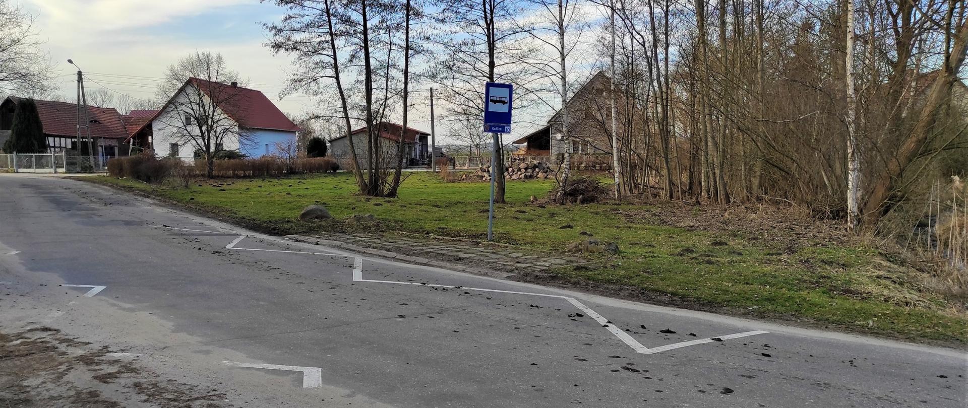 widok drogi przeznaczonej do remontu we wsi Koźlice, na drodze linie oznaczające przystanek autobusowy