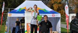 Olek Dziemiańczyk trzyma dyplom, stoi na podium pozuje do zdjęcia z trenerem